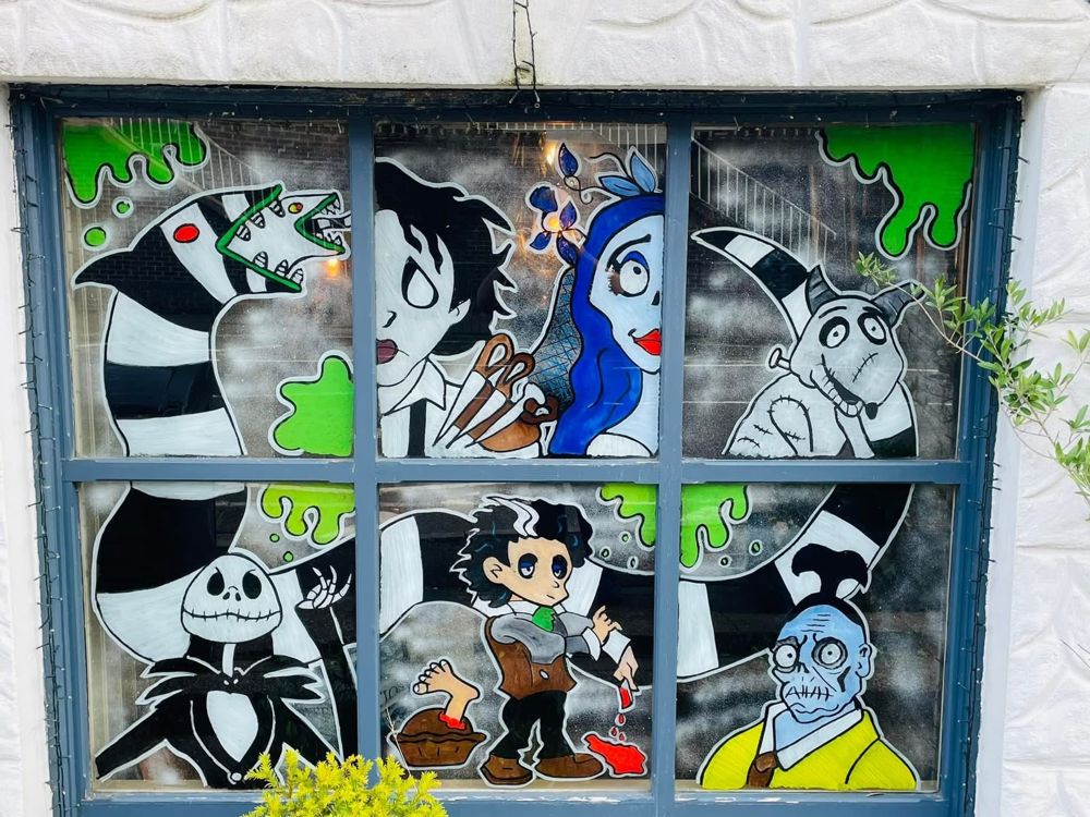 A six-pane window painted with spooky film characters in black, white and green
