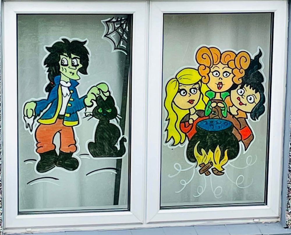 Three witches round a bubbling cauldron and a black cat, painted across two panes