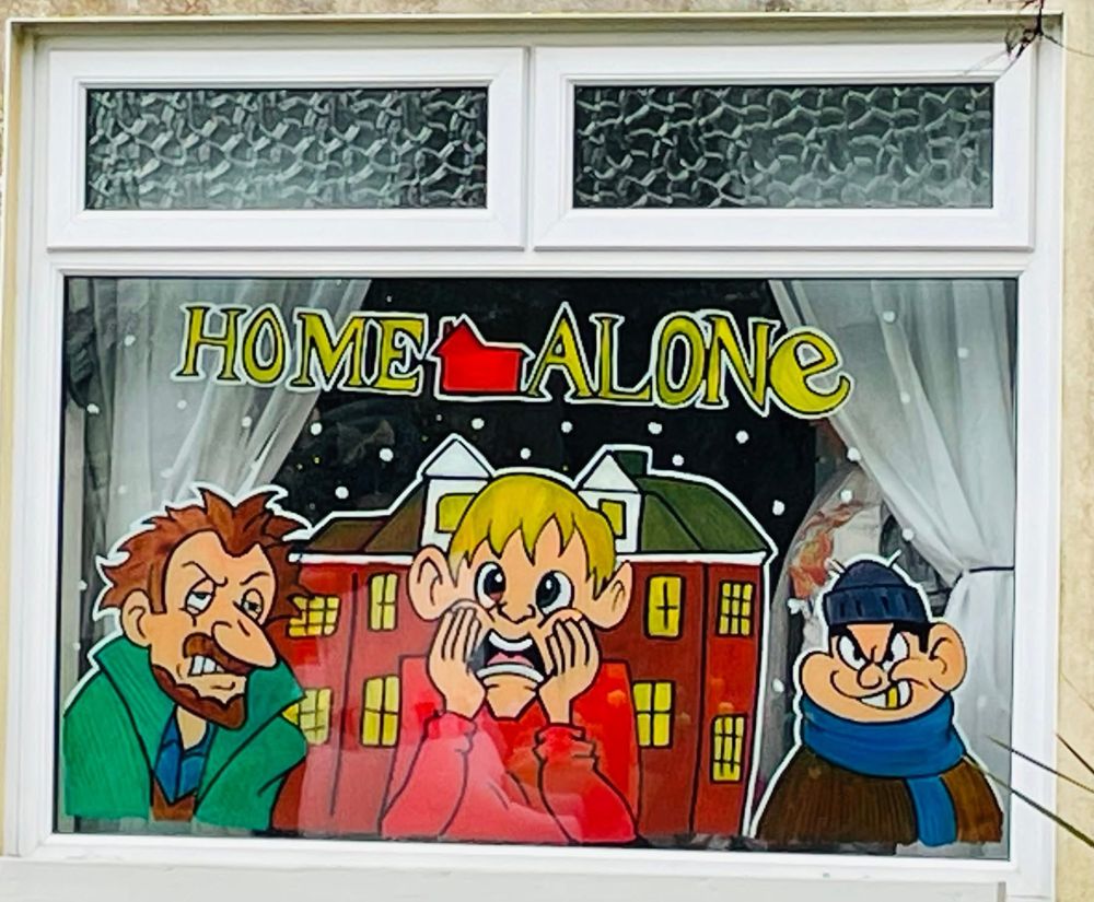 A Christmas film scene painted on a window, with a boy and two burglars in front of a snowy house