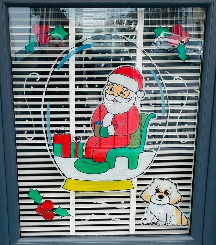 A painted window showing Santa in a snow globe with presents, holly and a little dog